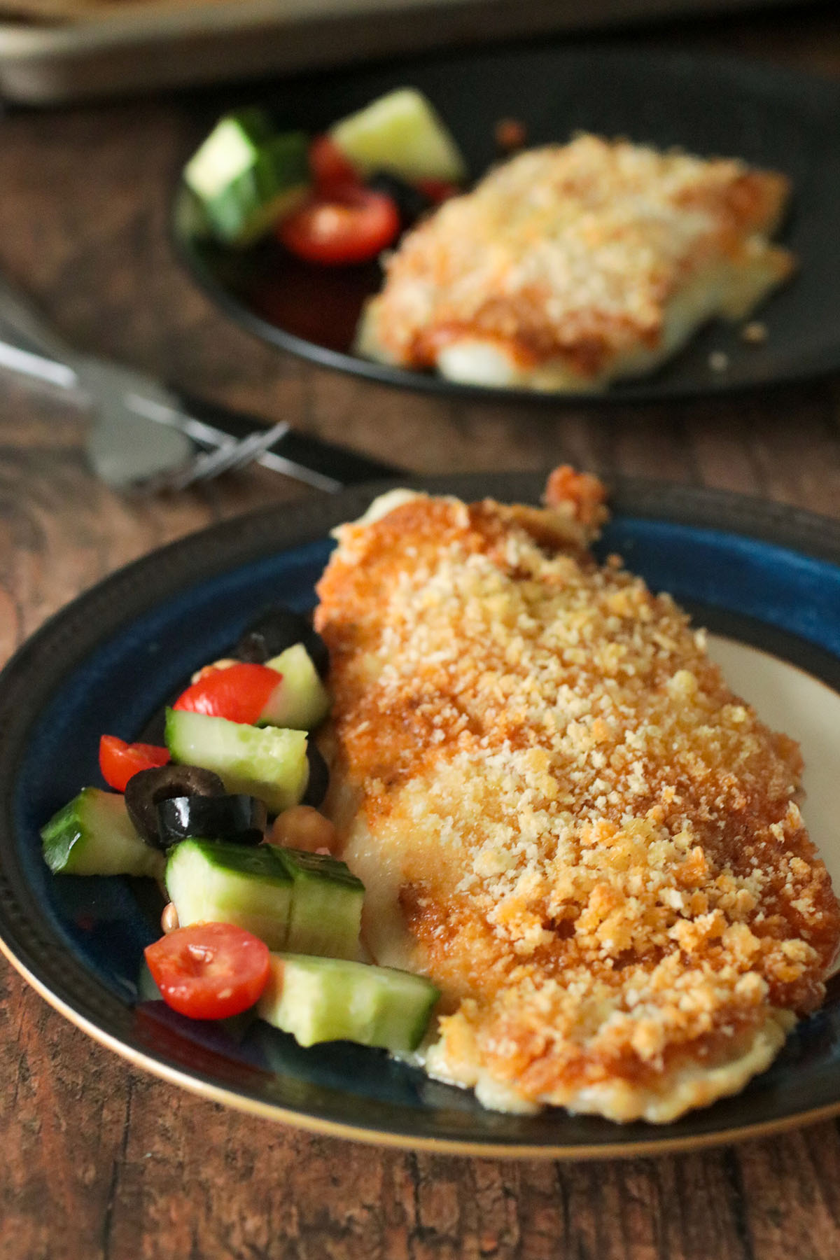 Baked fish fillet served on a plate with veggies on the side.