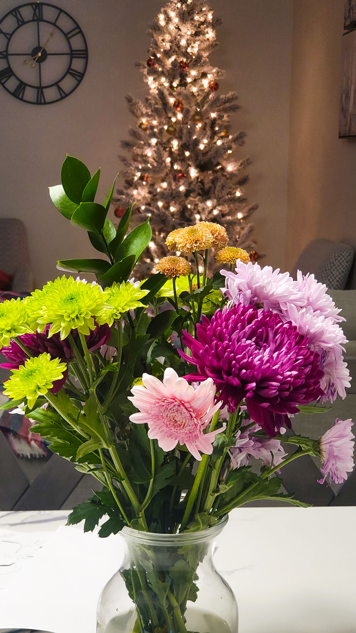 Flowers on a vase with a Christmas tree in the background. You are Love.